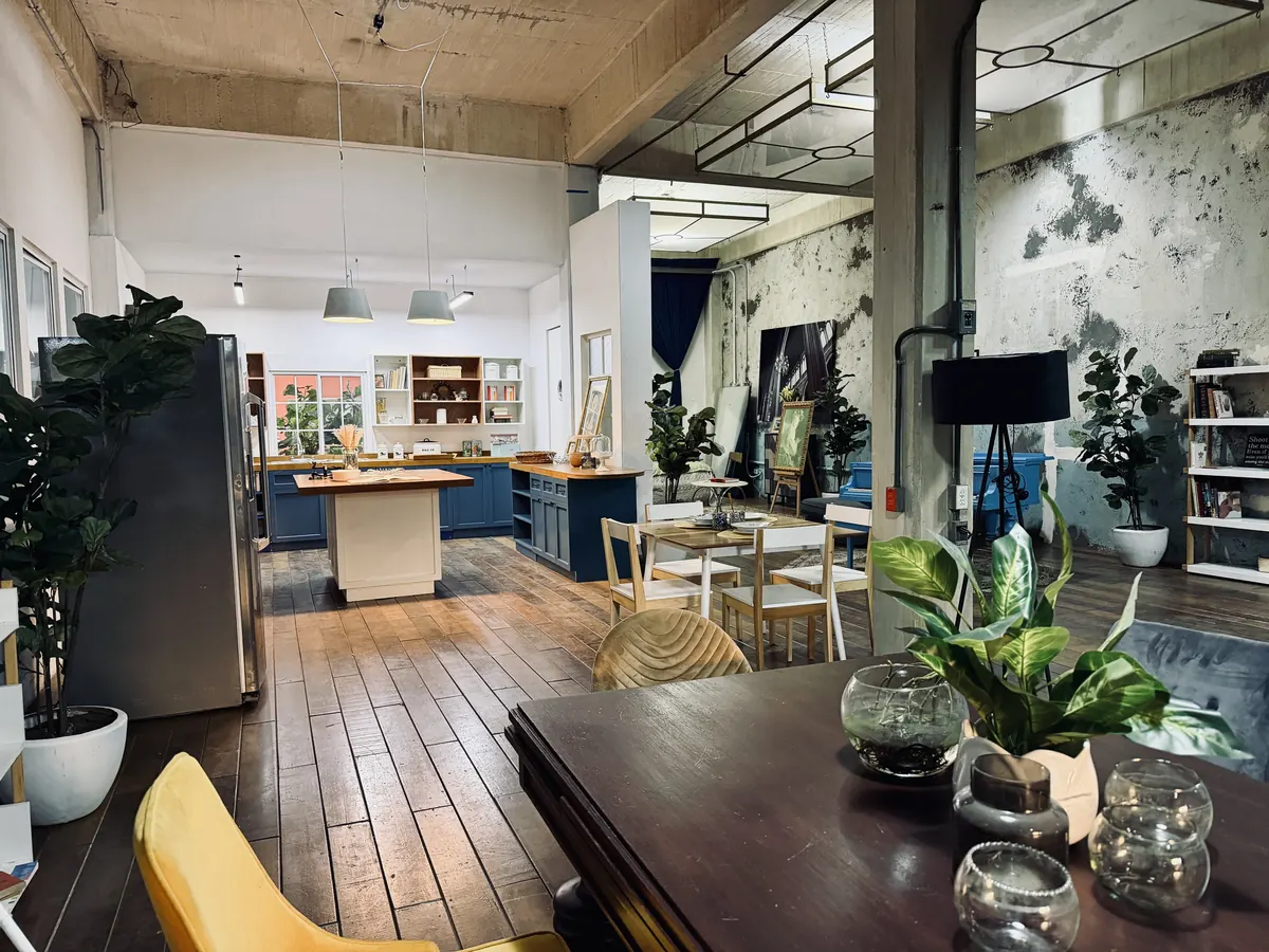 Cocina abierta de Loft 3 con isla de madera, comedor y muros de concreto aparente