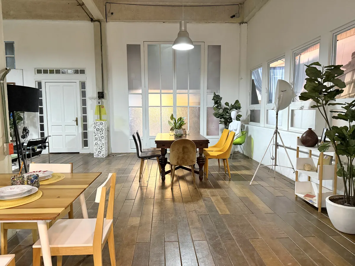 Comedor de Loft 3 junto a ventanales blancos, con piso de madera y sillas amarillas