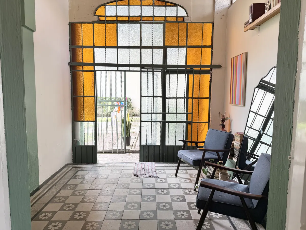 Entrada de Casa Popotla con vitral ámbar, mosaicos y mecedora de madera